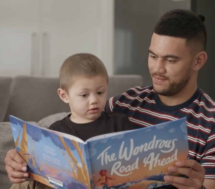 Father reading a book to his kid from the Redkite Book Club service which provides free resources for cancer patients